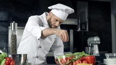 厨师用慢动作调味蔬菜。厨师在厨房烹饪新鲜食物.